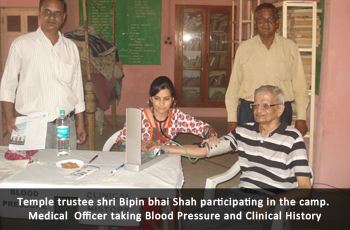 Temple trustee shri Bipin bhai Shah participating in the camp. Medical Officer taking Blood Pressure and Clinical History